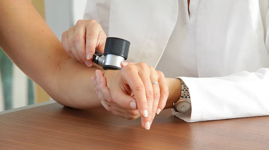 Untersuchung eines Muttermals am Arm mit dem Dermatoskop Untersuchung eines Muttermals am Arm mit dem Dermatoskop